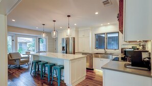 Une cuisine moderne avec des meubles blancs, des appareils en acier inoxydable et un îlot central doté de tabourets de bar.
