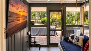 Une chambre dotée d’une grande fenêtre, d’un ventilateur de plafond, d’un lit agrémenté d’oreillers sur le thème de la marine, et offrant une vue sur un jardin.