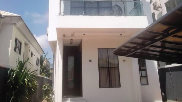 Un bâtiment moderne à deux  étages, doté d’un balcon, de grandes fenêtres et d’une entrée abritée.