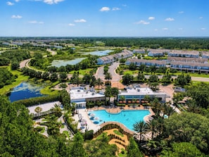 A resort with a large swimming pool, multiple guest buildings, and surrounding greenery.