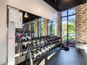 A gym with a mirrored wall, dumbbells, and exercise equipment.