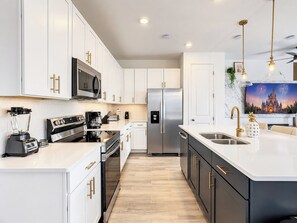 A modern kitchen with white cabinetry, stainless steel appliances, and a large island with a sink.