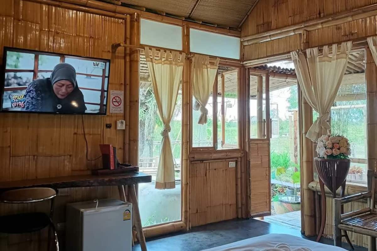 A room with a bed, a desk, a television, and a window with curtains.