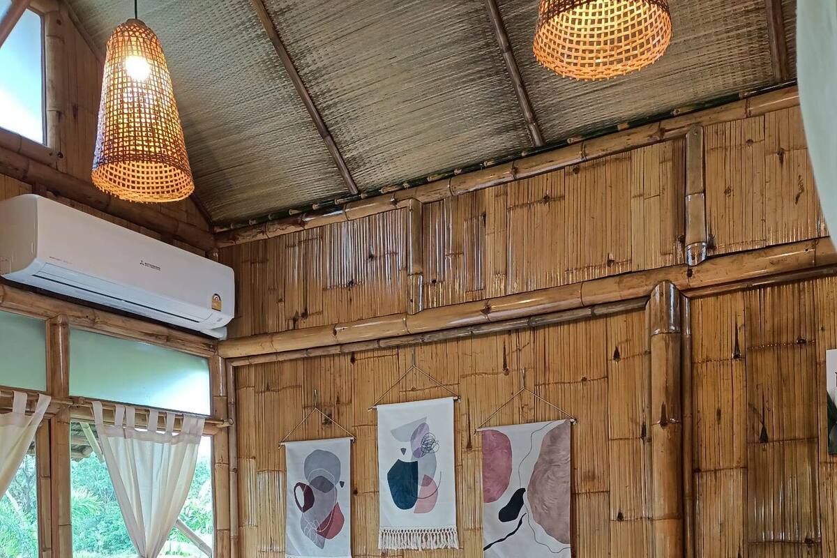A room with a bed, two wall-mounted lights, and three abstract wall art pieces.