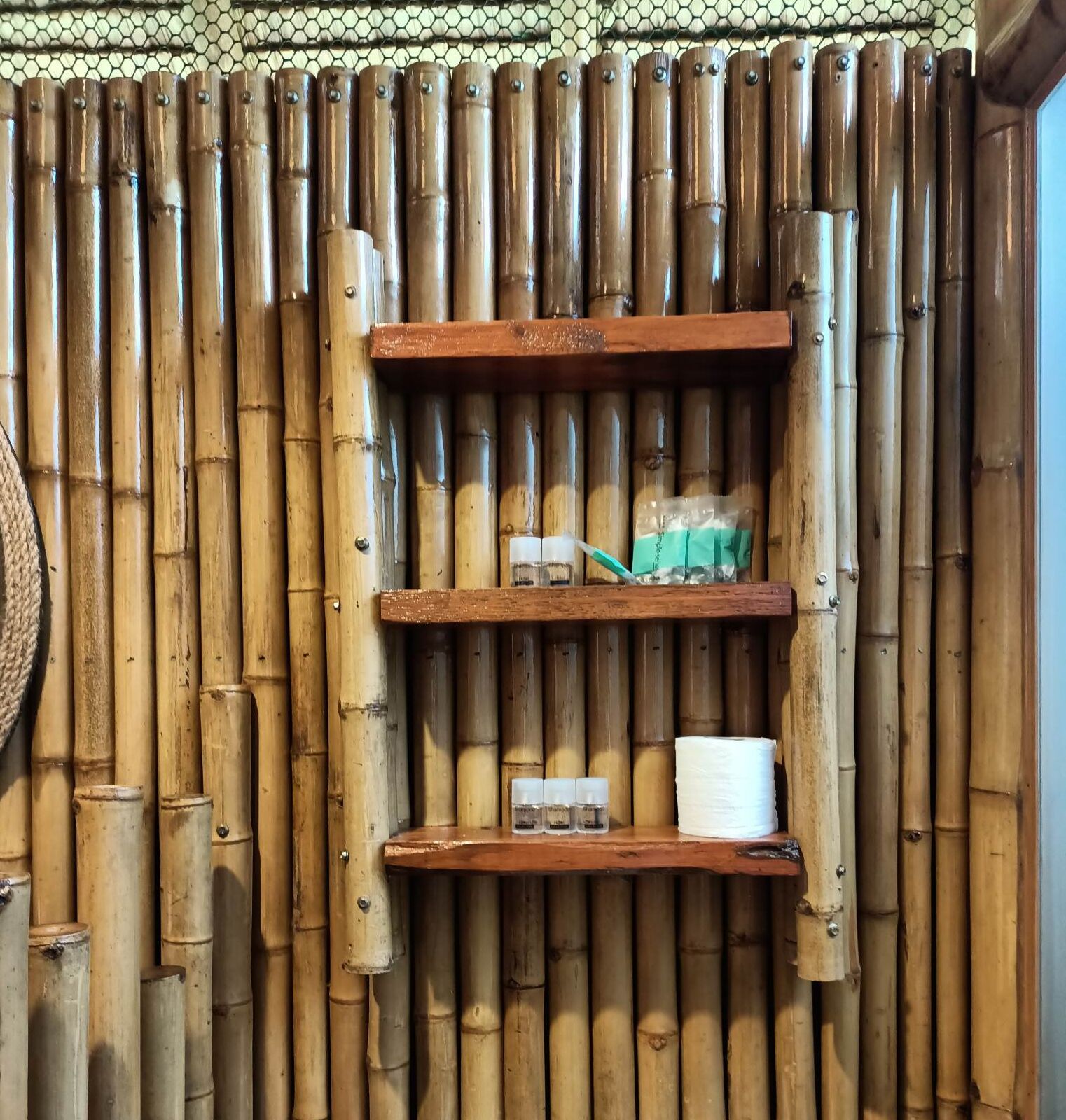A bamboo wall with shelves holding toiletries and a woven basket.