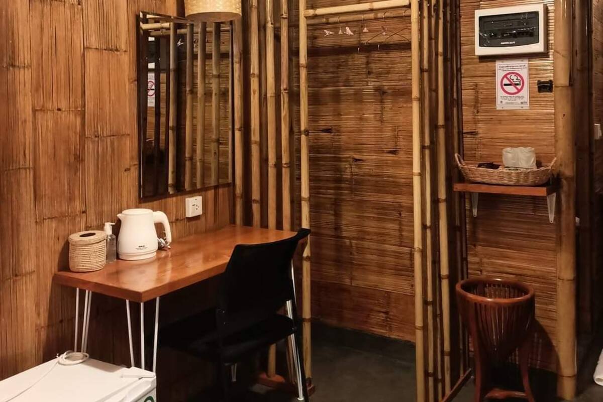 A wooden interior with a table, chairs, a clock, and a hanging light fixture.
