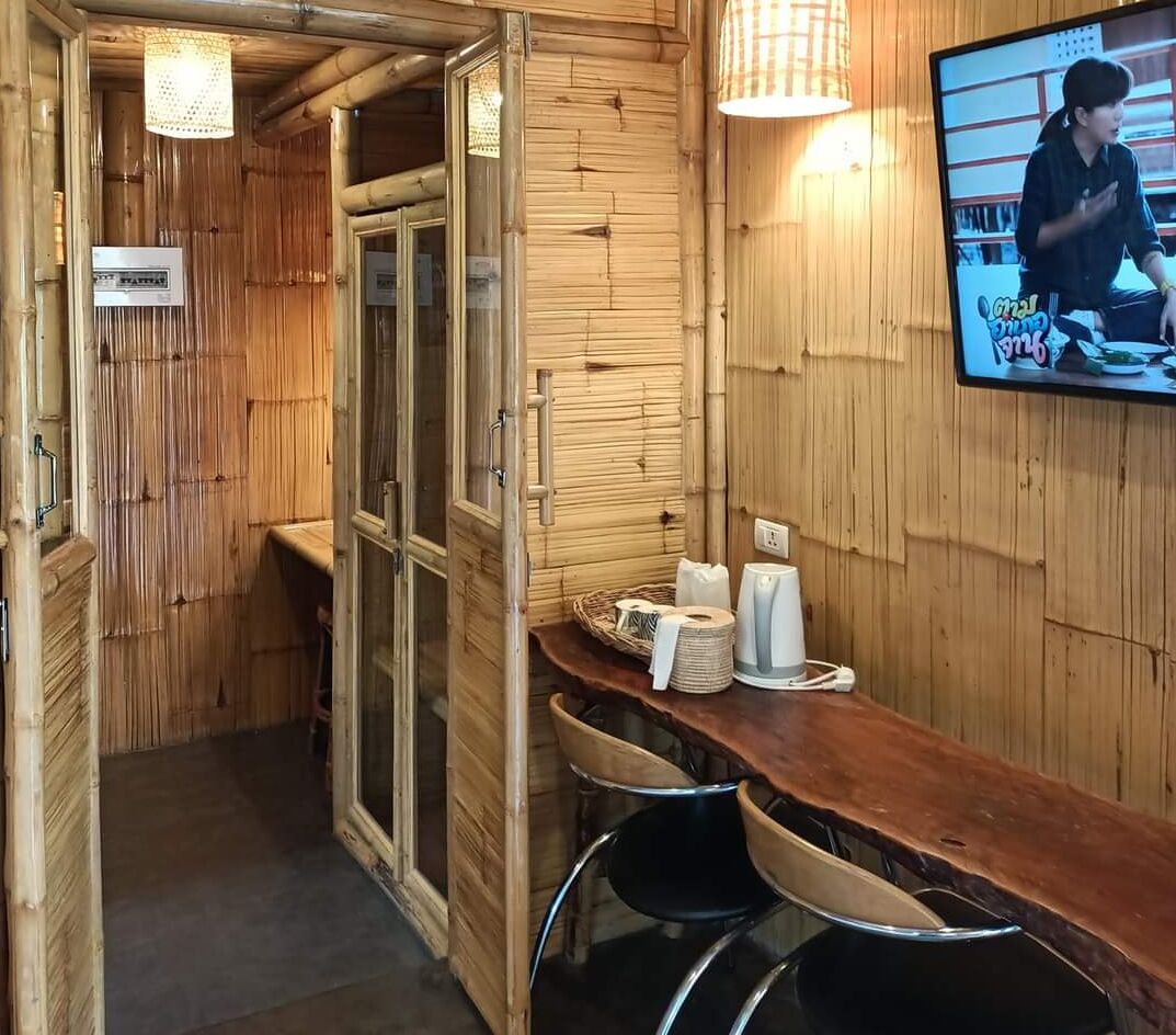 Un interior de madera con una zona de bar, una pantalla de televisión y un letrero que indica un restaurante.