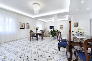 A dining area with a glass table, blue upholstered chairs, and a chandelier. - AMORE RENTALS - Villa Flavia with Private SPA, Swimming Pool, Terraces, Sea View (Sorrento)