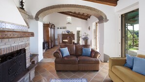 A spacious living area with a fireplace, a sofa, and a yellow armchair. - AMORE RENTALS - Casa I Giardini di Sorrento with Swimming Pool, Sauna, Sea View (Sorrento)