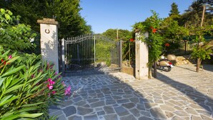 A stone-paved entrance with a metal gate, surrounded by greenery and a parked vehicle. - AMORE RENTALS - Casa I Giardini di Sorrento with Swimming Pool, Sauna, Sea View (Sorrento)