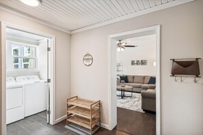 A laundry room with a washer and dryer, a wooden rack, and a mirror. - Cove Cottage - 3 Bedroom w/Private Pool. Sleeps 6. Quiet Community, Close to Fishing Marinas. 3 Home by RedAwning (Panama City)