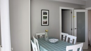 Un comedor con una mesa dispuesta para cuatro personas, sillas, un cuenco, un jarrón y un cuadro en la pared.