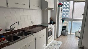 Una cocina moderna con armarios blancos, un lavamanos de acero inoxidable, un horno empotrado y una ventana con vistas.