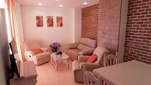 Una sala de estar con un juego de sofá, una mesita de centro con flores y una pared de ladrillo.