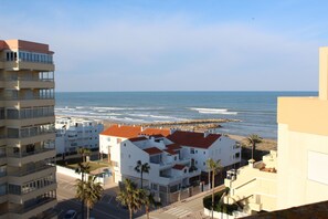 A coastal residential area with multi-story buildings, a beach, and a rocky breakwater.