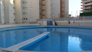 Una piscina con solárium alicatado, rodeada de edificios residenciales altos.