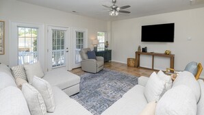 Un salon avec un canapé gris, un tapis bleu à motifs et un ventilateur de plafond.