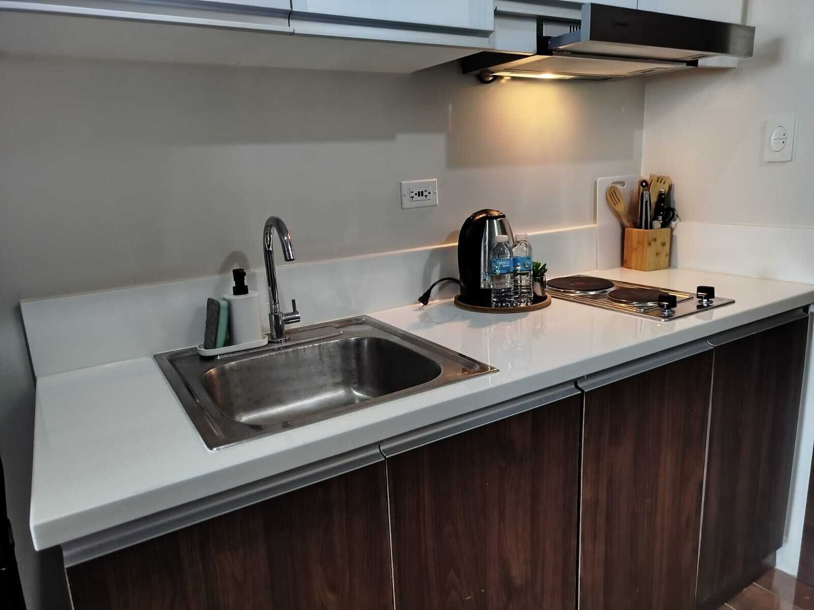 A modern kitchen with a stainless steel sink, a kettle, and a knife block.
