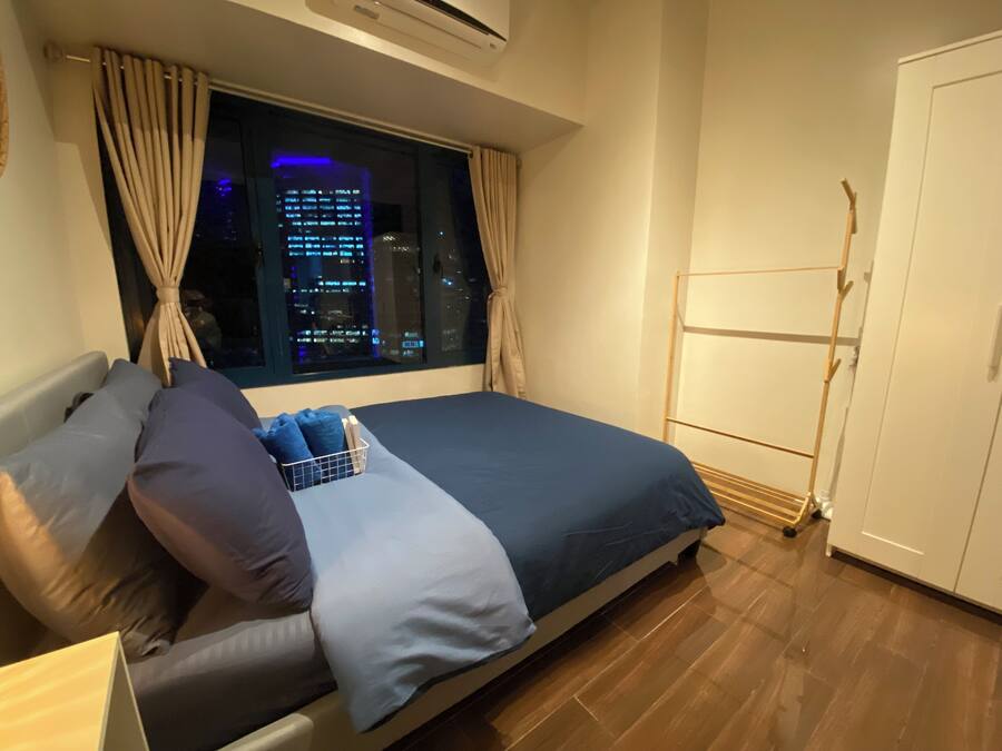 Een slaapkamer met een bed, een raam met gordijnen, een houten vloer en een kledingkast.