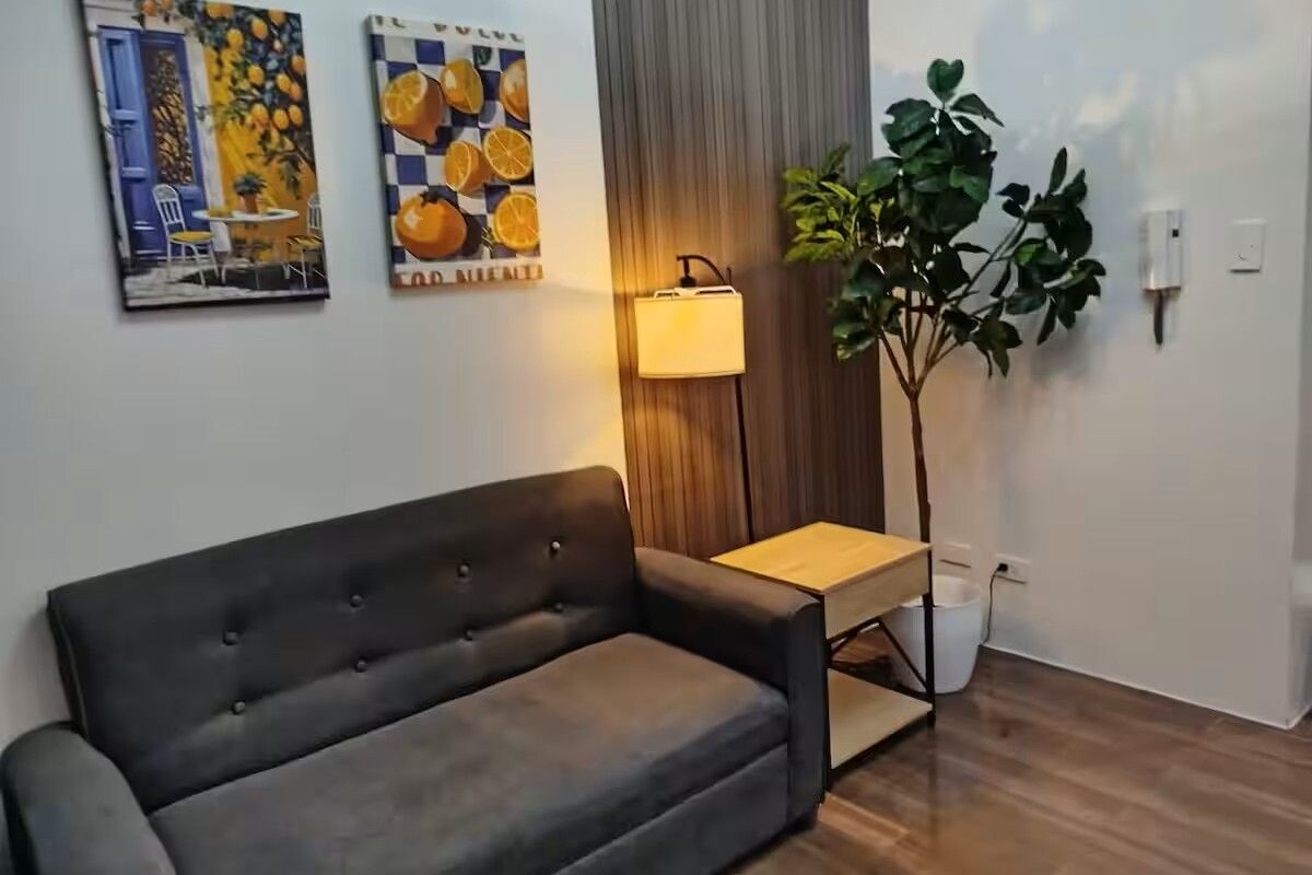 A modern living room with a sofa, a small table, a lamp, and two wall-mounted paintings.