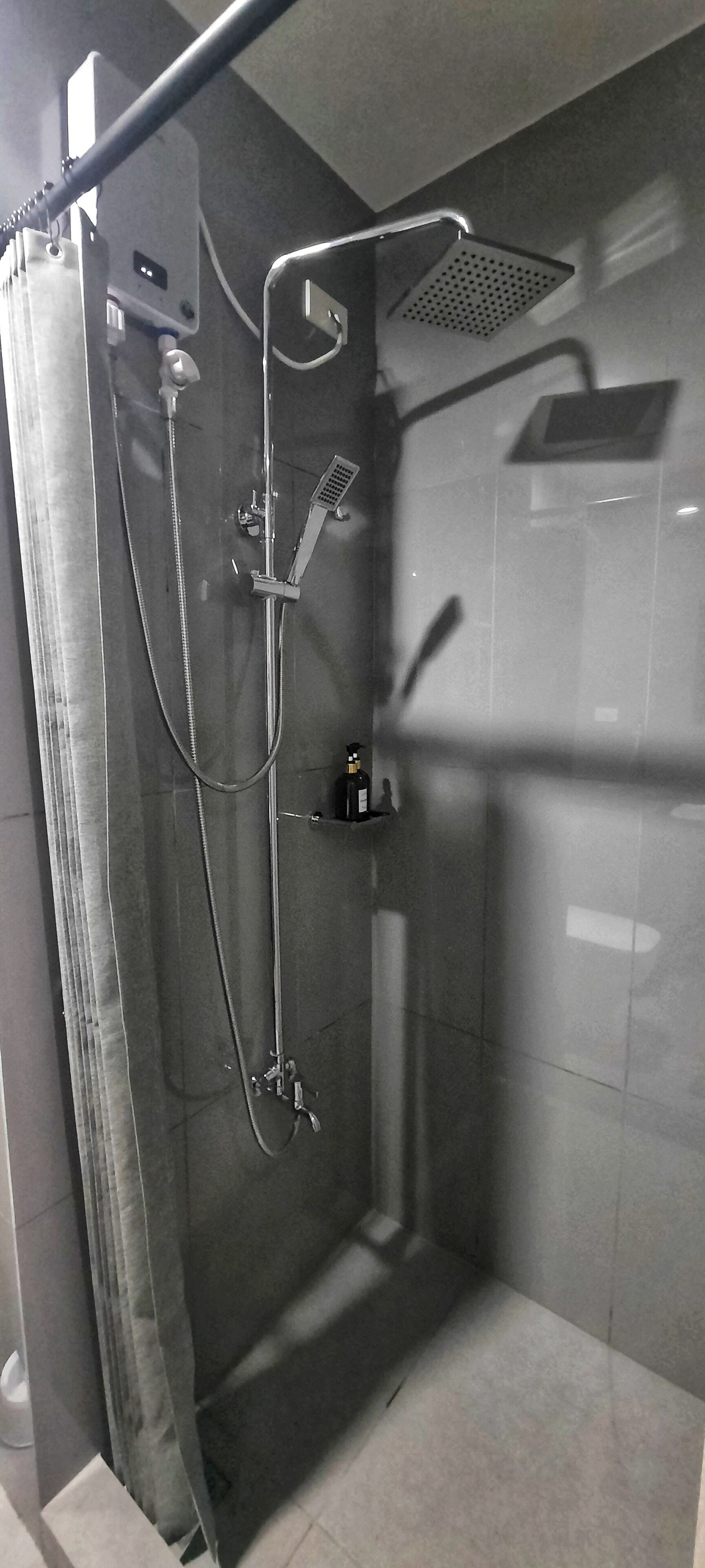 A modern shower area with a handheld showerhead, a fixed showerhead, and a handheld shower attachment.