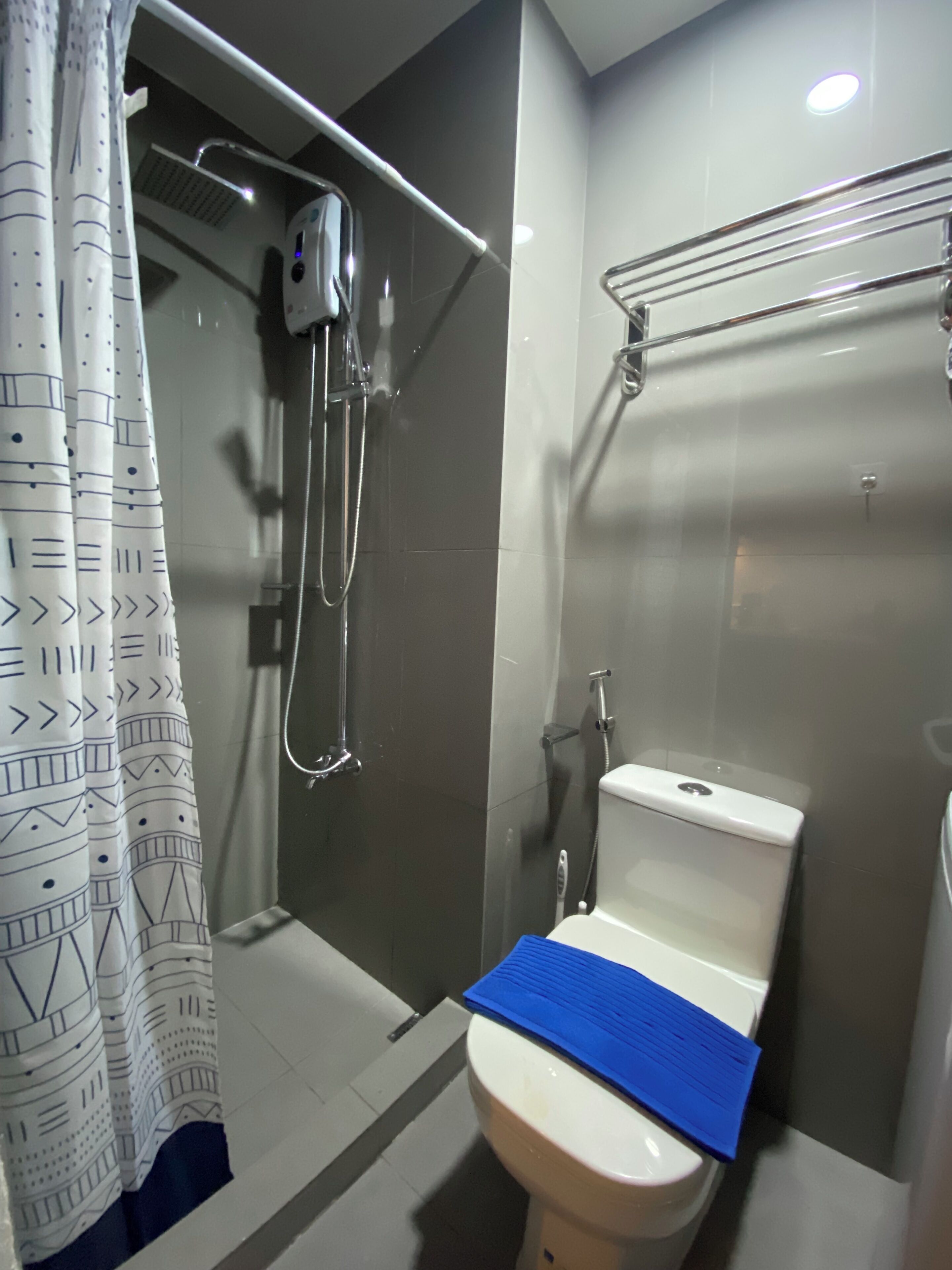 Een moderne badkamer met een douche, toilet en een handdoekrek.