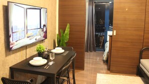 A hotel room with a dining area, a bed, a TV, and a view of the city. - SMDC Air Residences Makati (Makati)