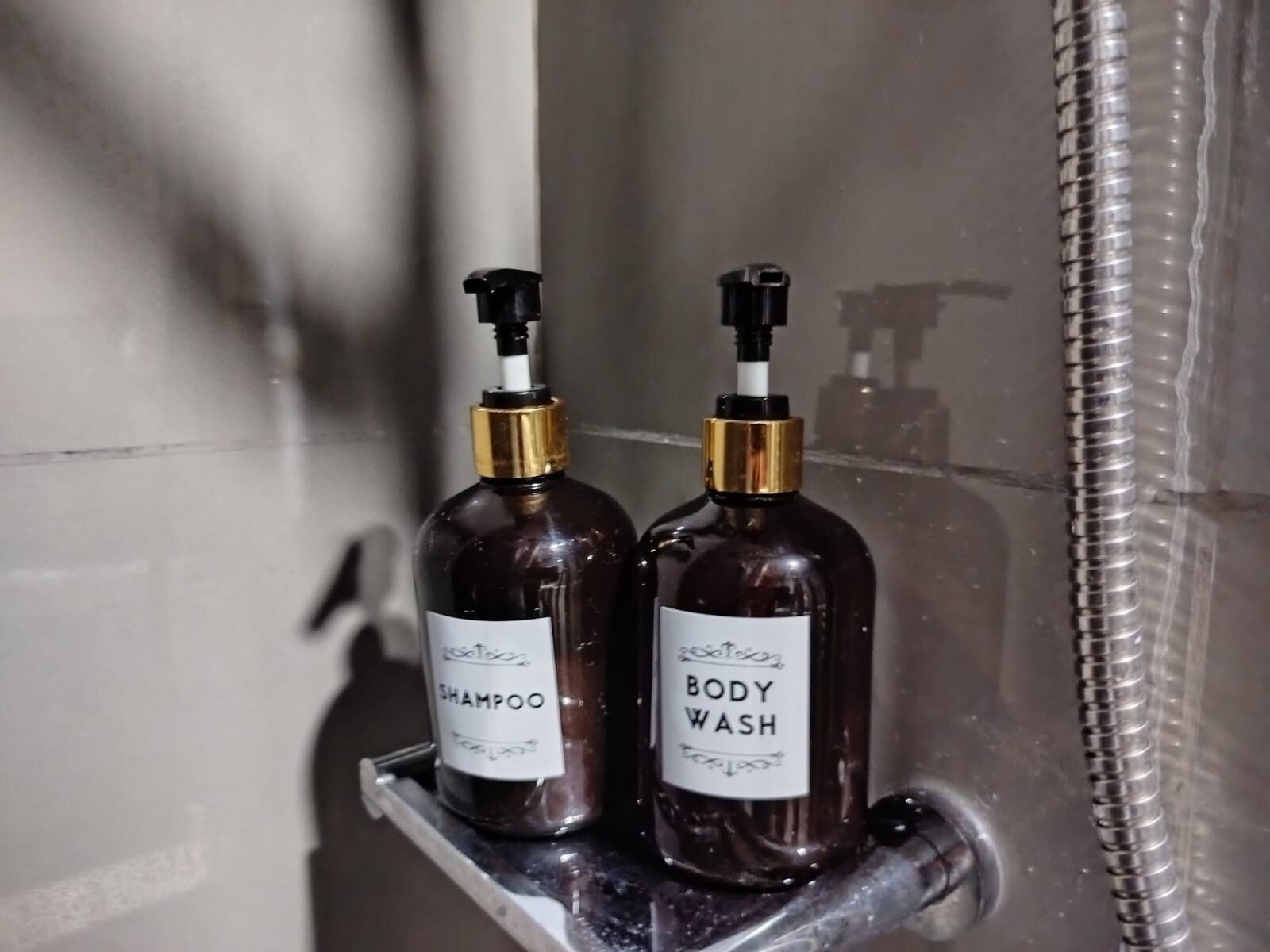 Two bottles of shampoo and body wash on a bathroom shelf.