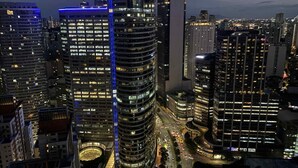 A high-rise building with a distinctive curved design, multiple floors, and illuminated windows. - SMDC Air Residences Makati (Makati)