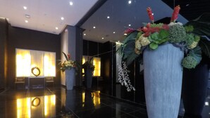 A lobby with a polished floor, large potted plants, and a reception desk with a wreath. - SMDC Air Residences Makati (Makati)