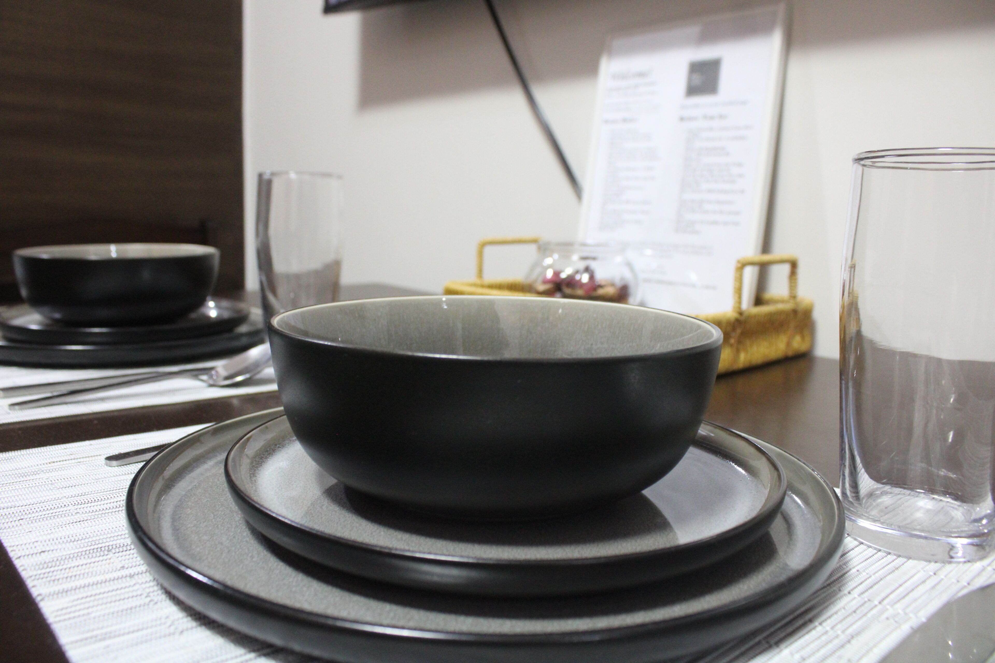 A dining table with stacked plates, a bowl, and a glass.