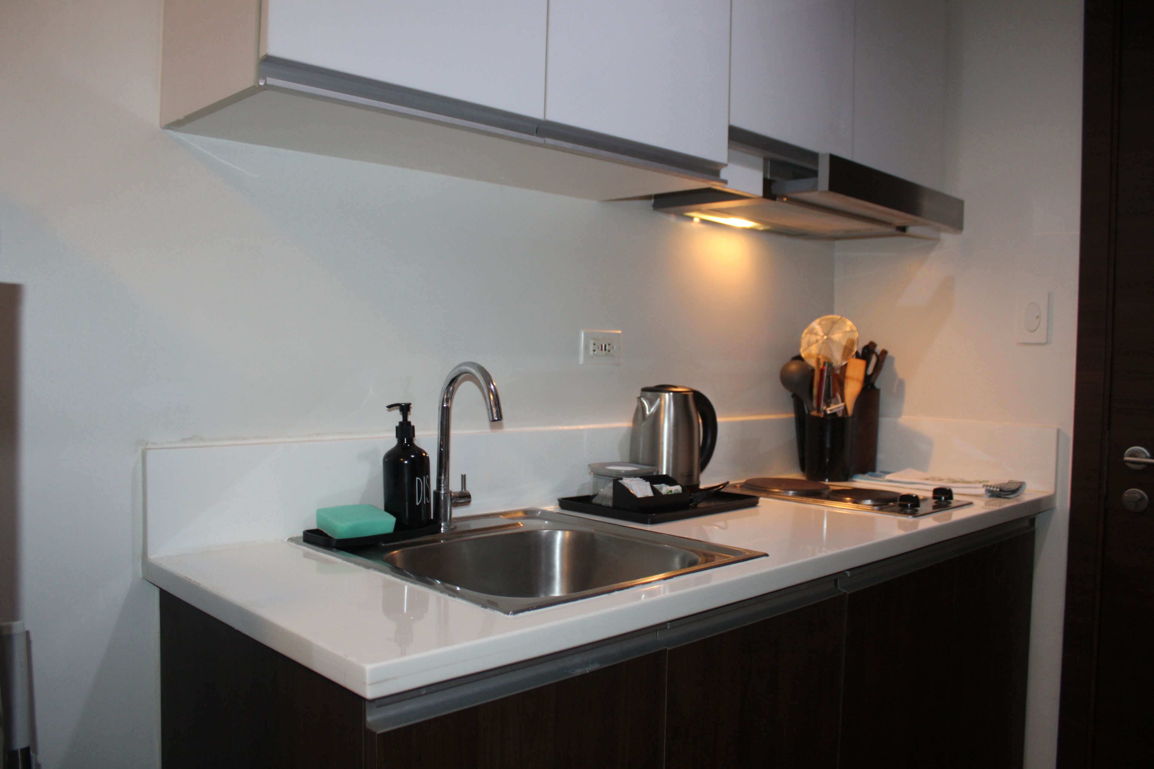A modern kitchen with a stainless steel sink, a kettle, and a knife block.