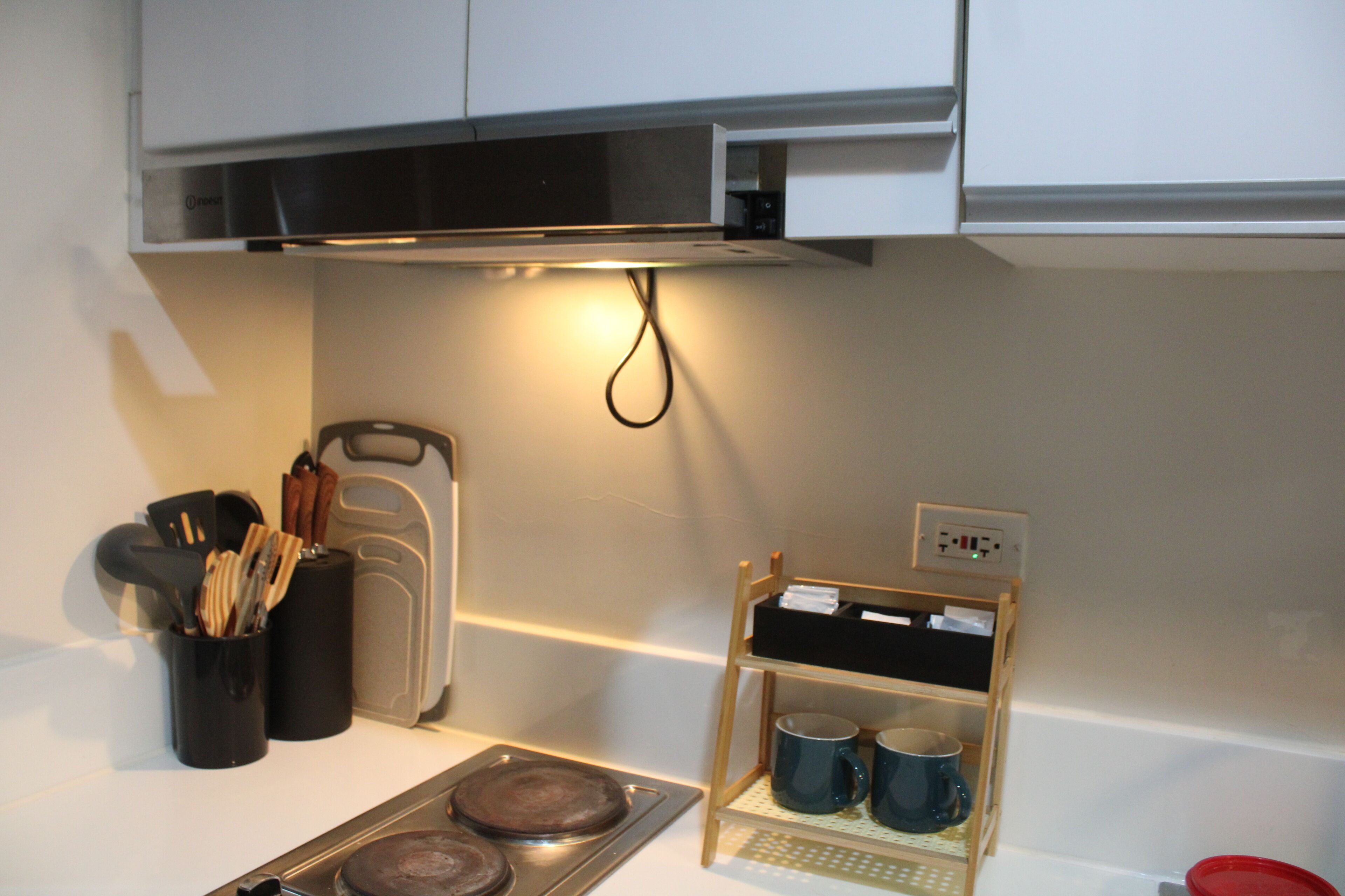 A kitchen with a microwave, a coffee maker, and a mug rack.