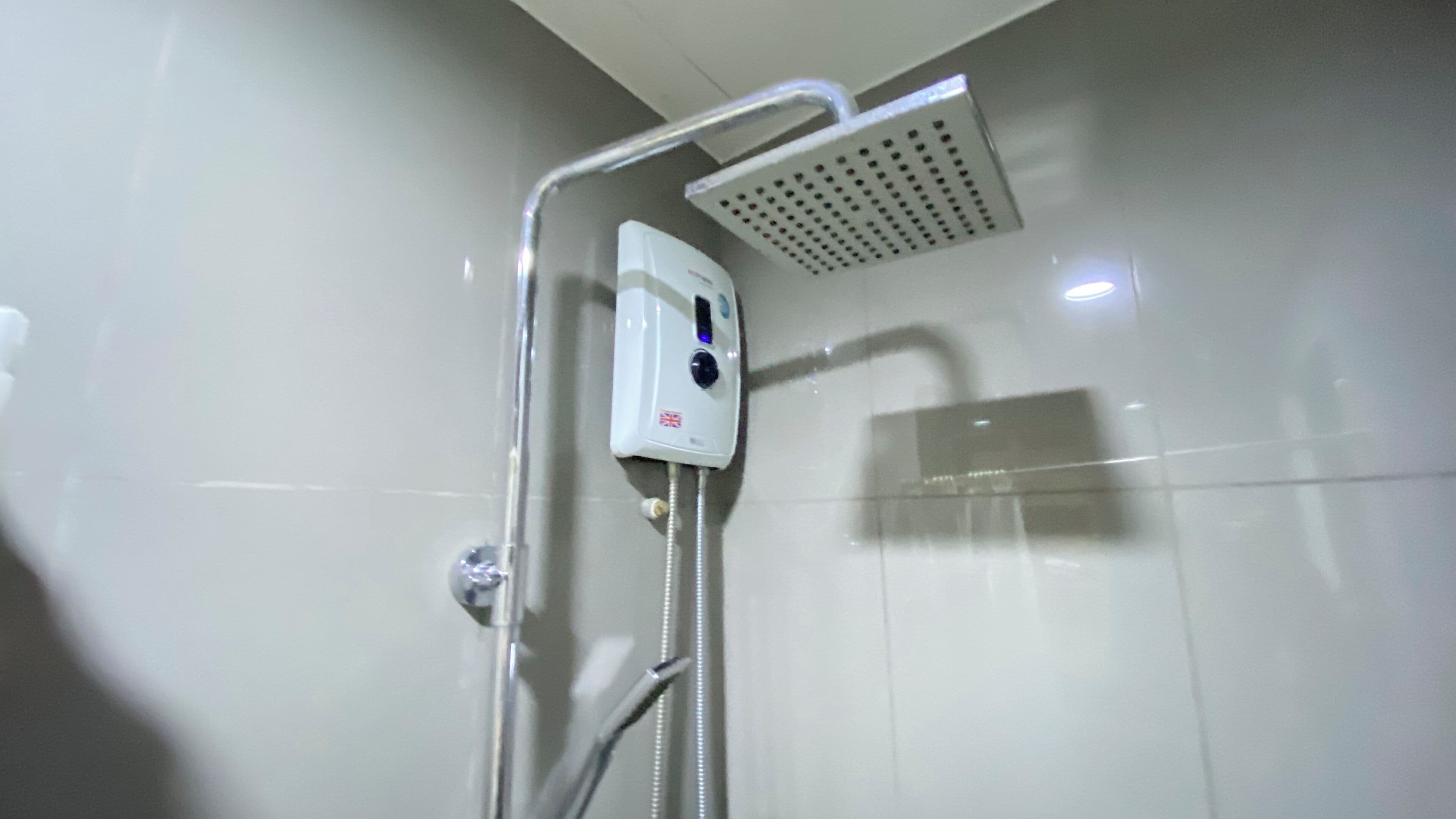 Une douche moderne dotée d’un pommeau de douche à main et d’un panneau de commande fixé au mur.