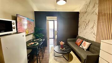 Un espace de vie compact comprenant une kitchenette, un coin repas et un coin salon.