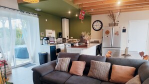 A modern living room with a grey sofa, a coffee table, and a kitchen in the background.