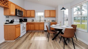 Une cuisine moderne avec des meubles en bois, un four à micro-ondes et un coin repas comprenant une table et des chaises.