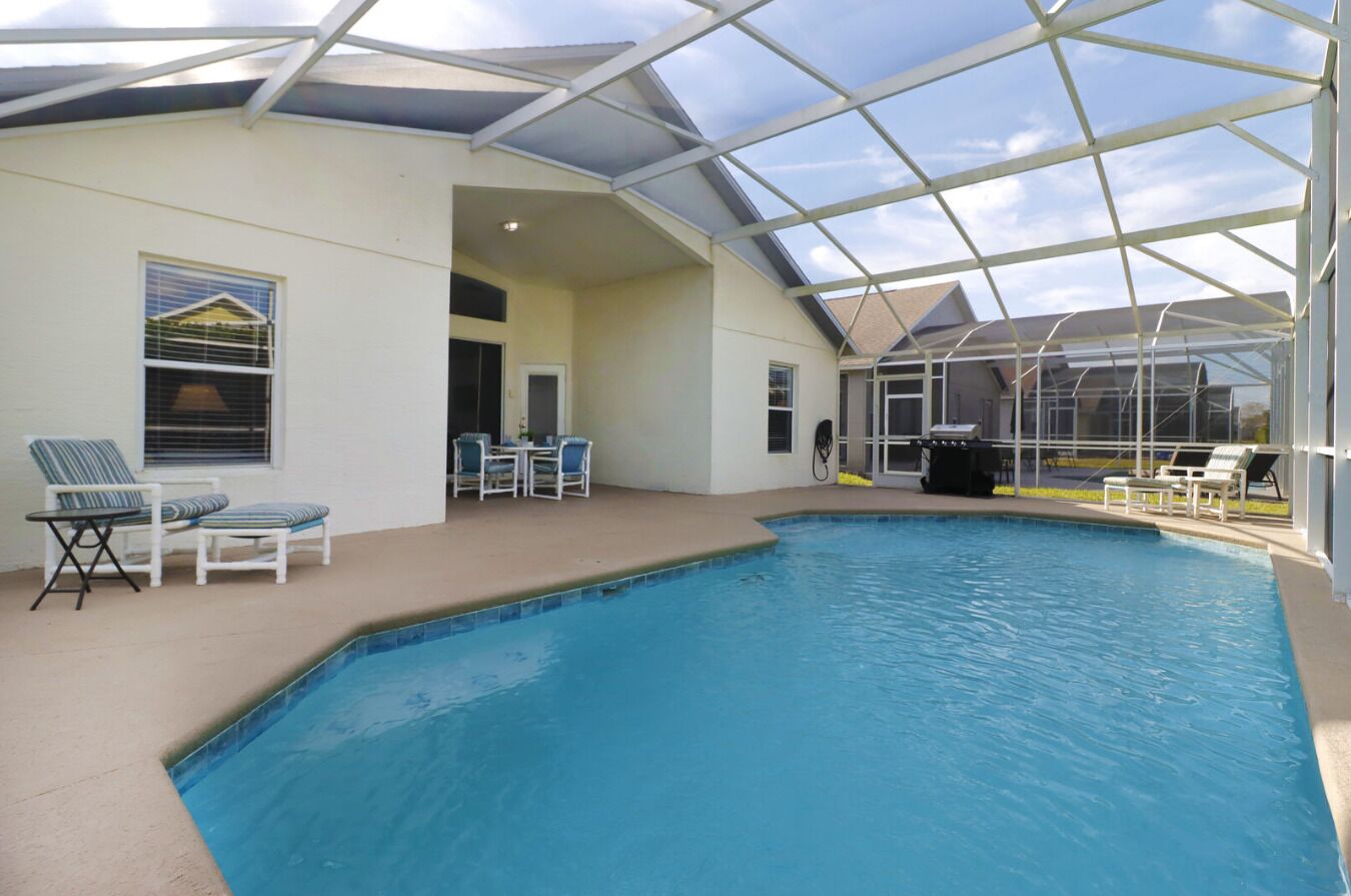 An indoor swimming pool with a glass ceiling, lounge chairs, and a view of the outside.