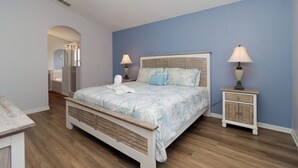 Une chambre à coucher comprenant un lit, des tables de chevet, une commode et un miroir.