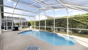Une piscine intérieure dotée d’un toit en verre, entourée d’une structure métallique blanche.