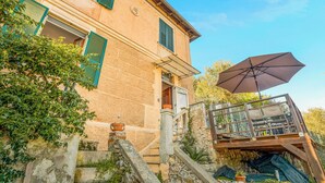 Un bâtiment en pierre doté d’un balcon, d’un grand parasol et d’un escalier menant à l’entrée.