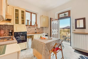 A kitchen with a dining area, a view of the outside, and a door leading to a balcony.