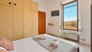 Une chambre à coucher avec un lit, une armoire, une télévision et une fenêtre donnant sur un beau paysage.