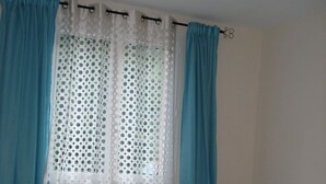 Un dormitorio con cama, cortinas y ventana.