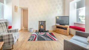 Una sala de estar con chimenea, televisor y dos sofás.