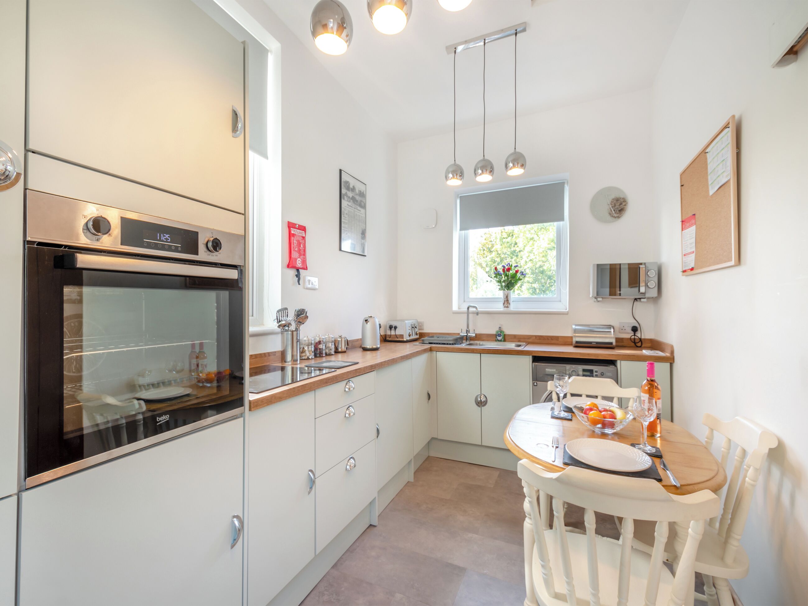 A modern kitchen with a built-in oven, a sink, and a dining area with a table and chairs.