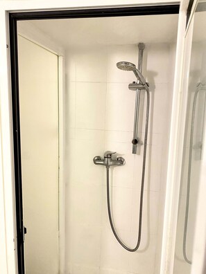 Une douche équipée d’un pommeau de douche à main et d’un pommeau de douche fixe, tous deux fixés au mur.