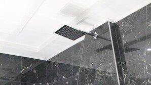 Una ducha moderna con cabezal de ducha de mano y panel de control en la pared.