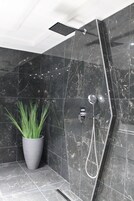 A modern shower with a handheld showerhead and a wall-mounted control panel.