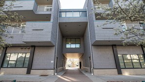 Un edificio moderno con entrada central, grandes ventanales y un camino de ladrillo que conduce a la entrada.
